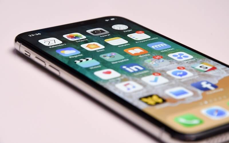 An iPhone X with front screen on, showing home screen and apps.