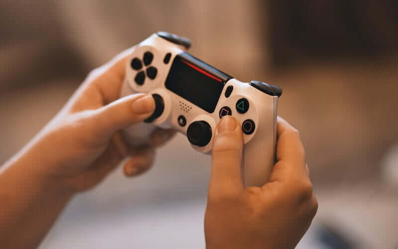 Person holding a white PS4 controller in hands