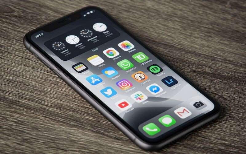 An iPhone 11 with the screen on, showcasing the home screen.
