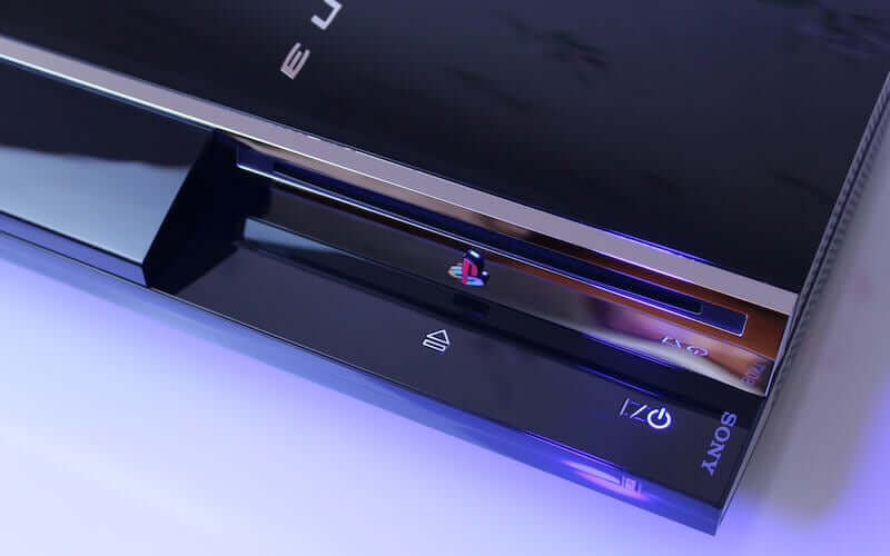 A close up of the disc tray area of a black shiny PlayStation 3 console