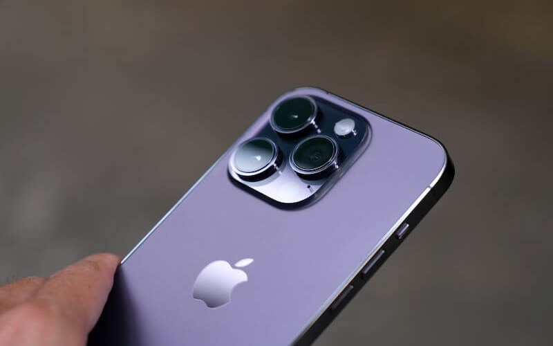 Close up of a dark purple iPhone being held in someone’s hand.