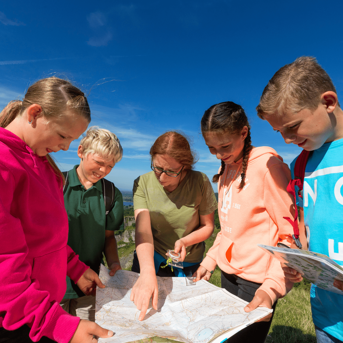 A group of students gather around an open map, whilst an instructor points out an area of interest