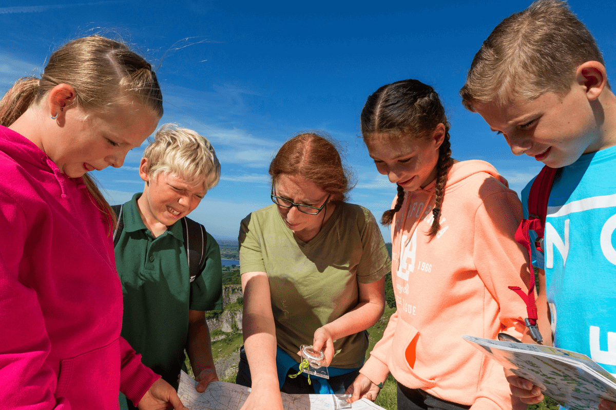 A group of students gather around an open map, whilst an instructor points out an area of interest