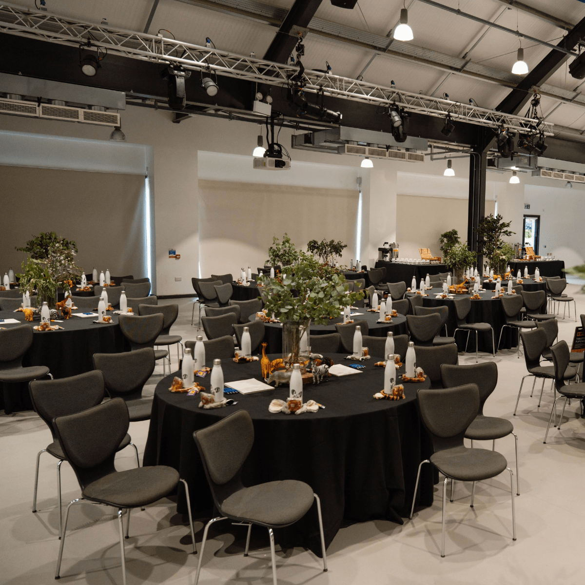 Tables set in cabaret style with black table cloths and leafy centrepieces