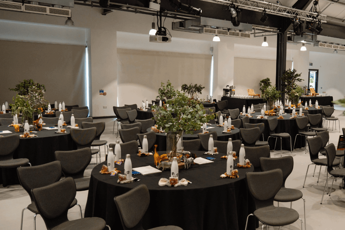Tables set in cabaret style with black table cloths and leafy centrepieces