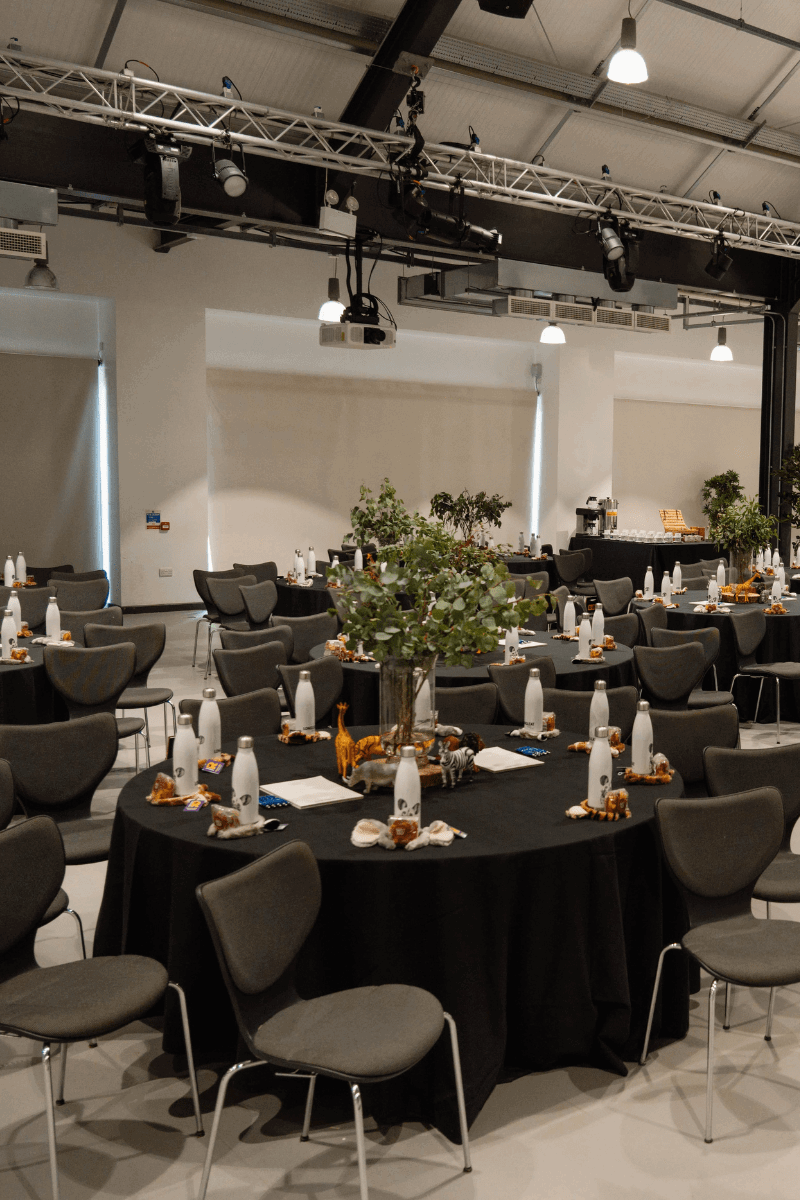 Tables set in cabaret style with black table cloths and leafy centrepieces
