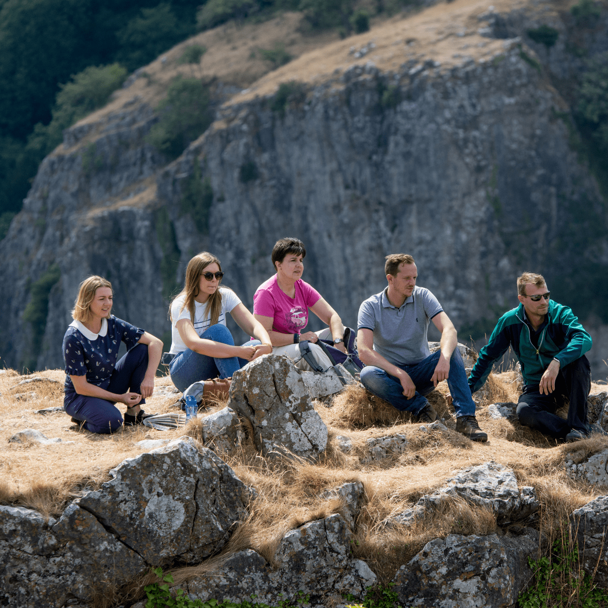 A group sit on the top of the cliff-top walk as they look out into the expansive view below