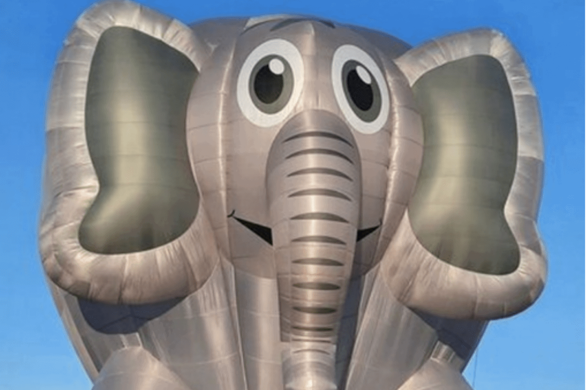 An elephant-shaped balloon in the air.,