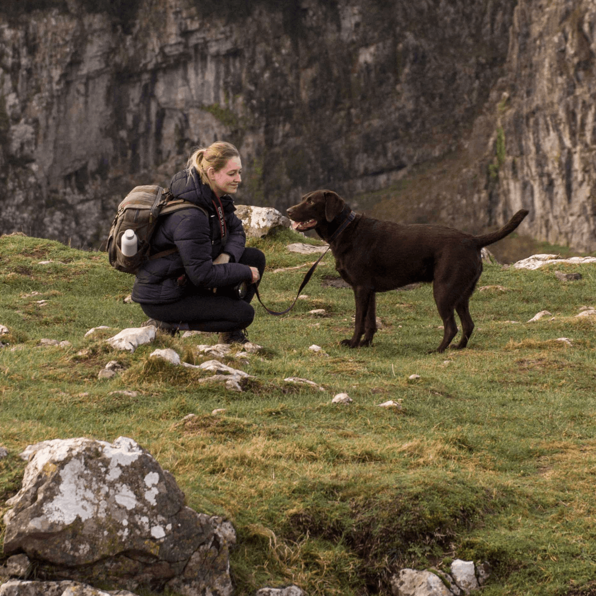 A visitor and her dog pose during their cliff-top walk at Cheddar