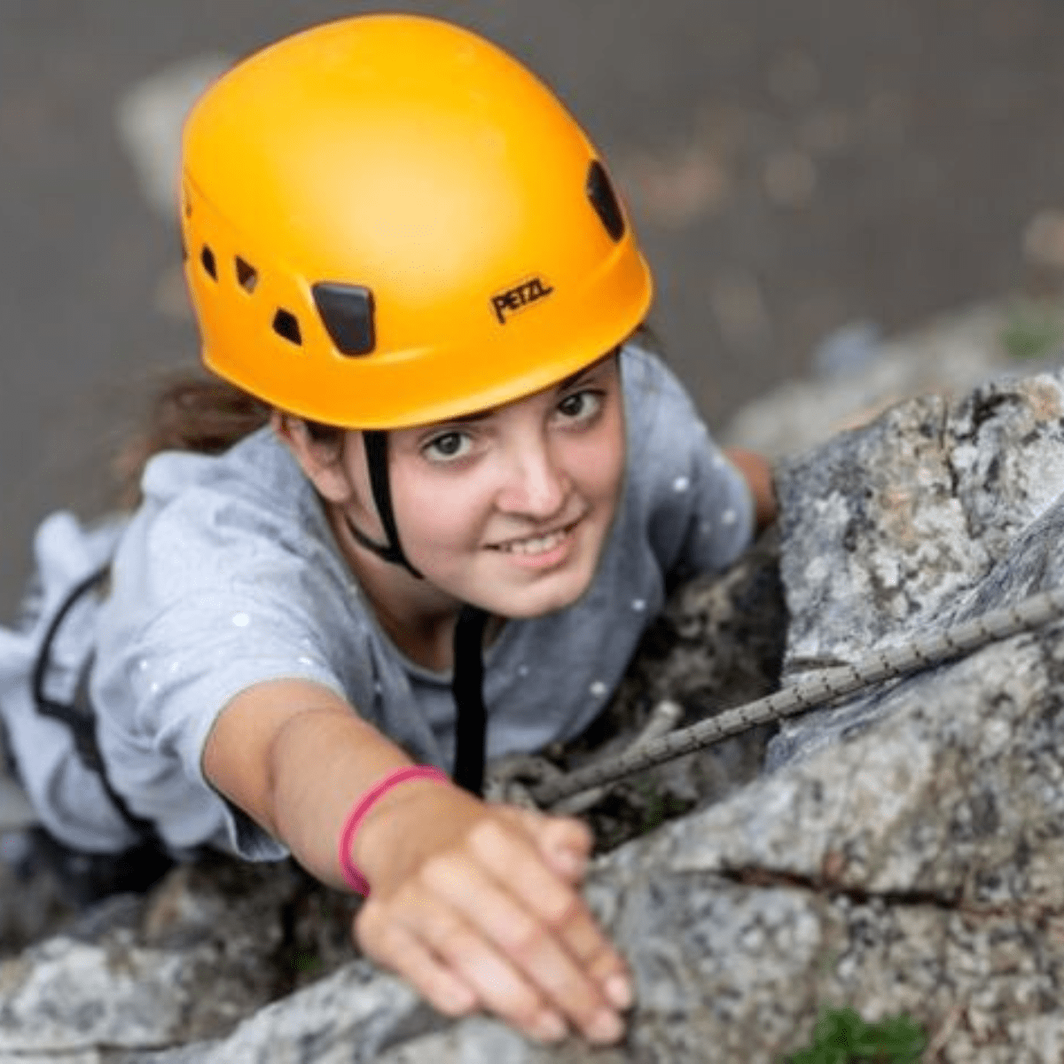 A visitor climbs one of the rock formations at Cheddar Gorge & Caves, whilst looking at the camera ahead of her