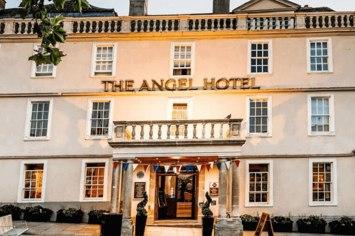 The Angel Hotel - A large white hotel building with pillars at the entrance and outdoor lighting.