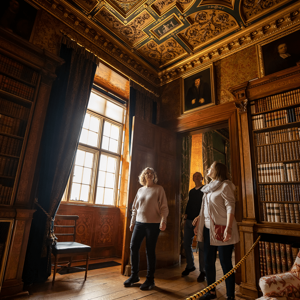 A small group of visitors look up whilst exploring the treasures of Longleat House