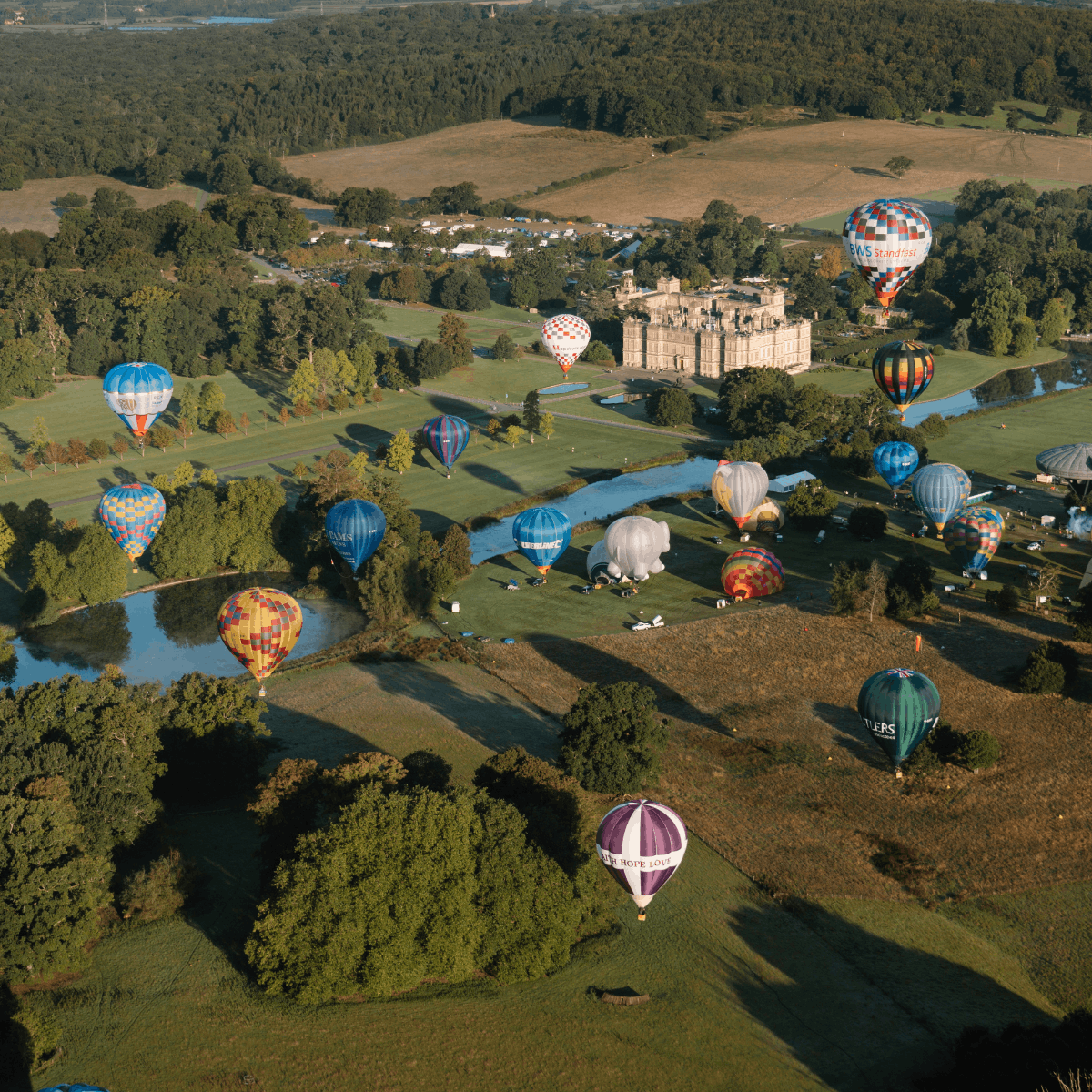 An aerial shot over Longleat House and grounds with a range of hot air balloons taking off
