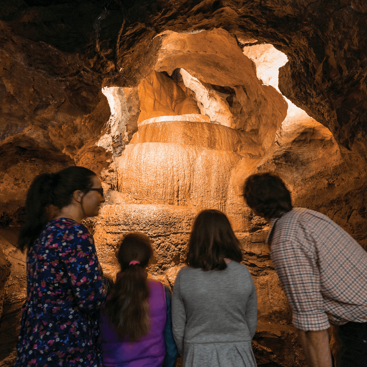 A family look up into a section of Gough's cave as water trickles down the cave structures