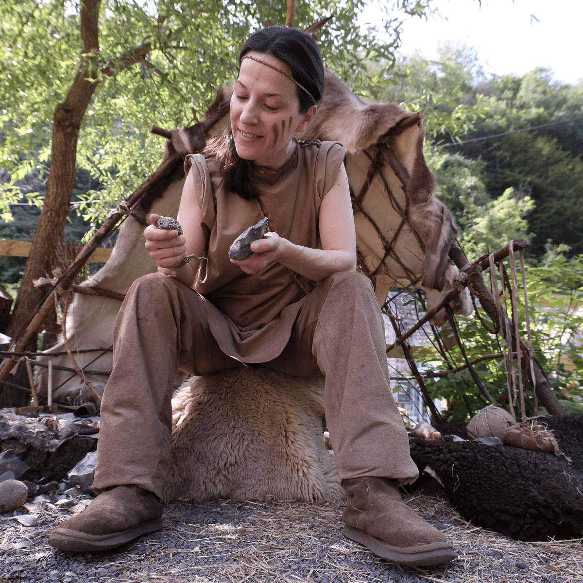 An actor demonstrates flint knapping whilst wearing prehistoric clothing