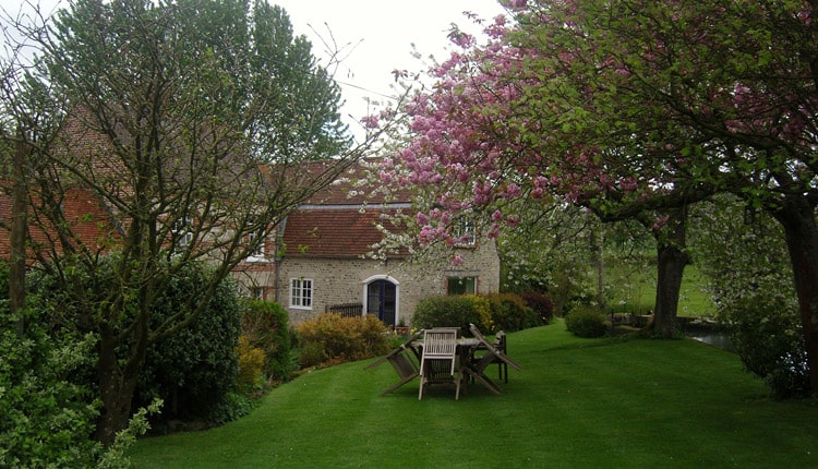 Mill Farm B&B - A stone building with a lawned garden and trees in bloom.