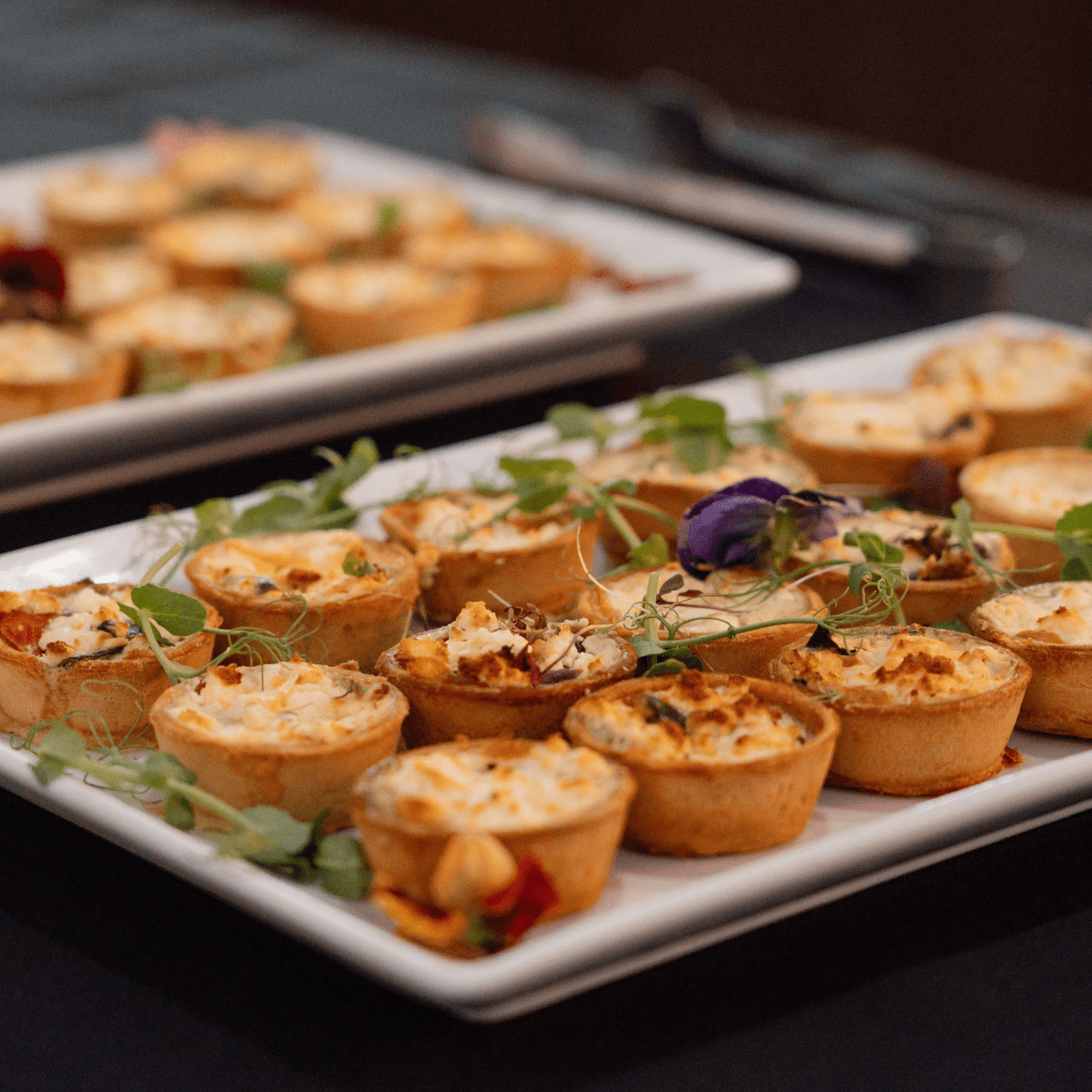 A plate of small canope tarts with decorative flower on top.