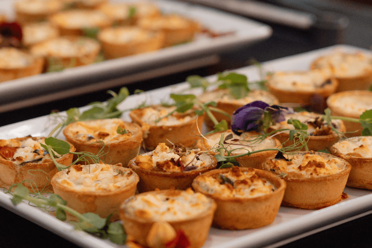 A plate of small canope tarts with decorative flower on top.