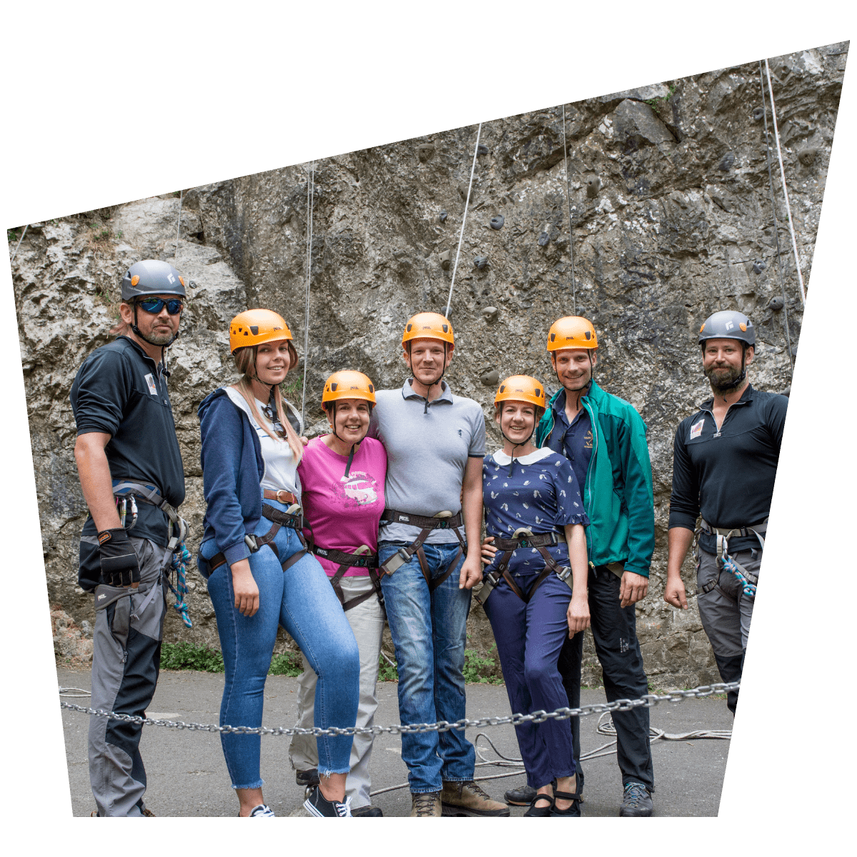 A group poses for a photograph in their climbing gear in front of a rock formation
