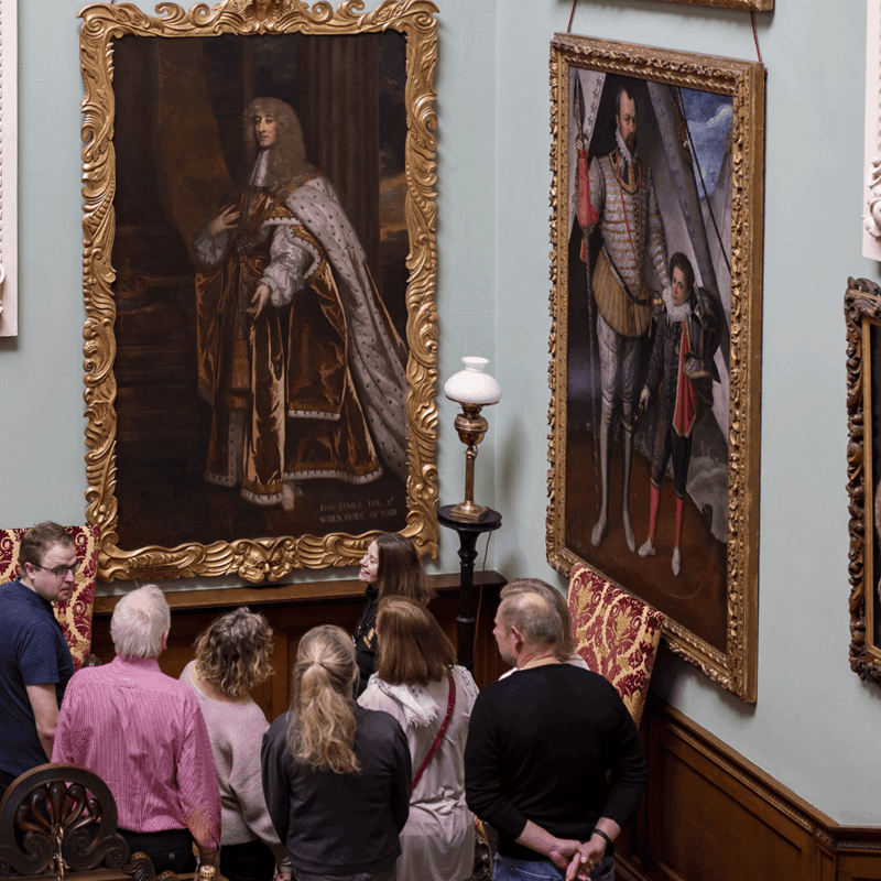 A group of visitors admire artwork decorating the walls on the grand staircase of Longleat House