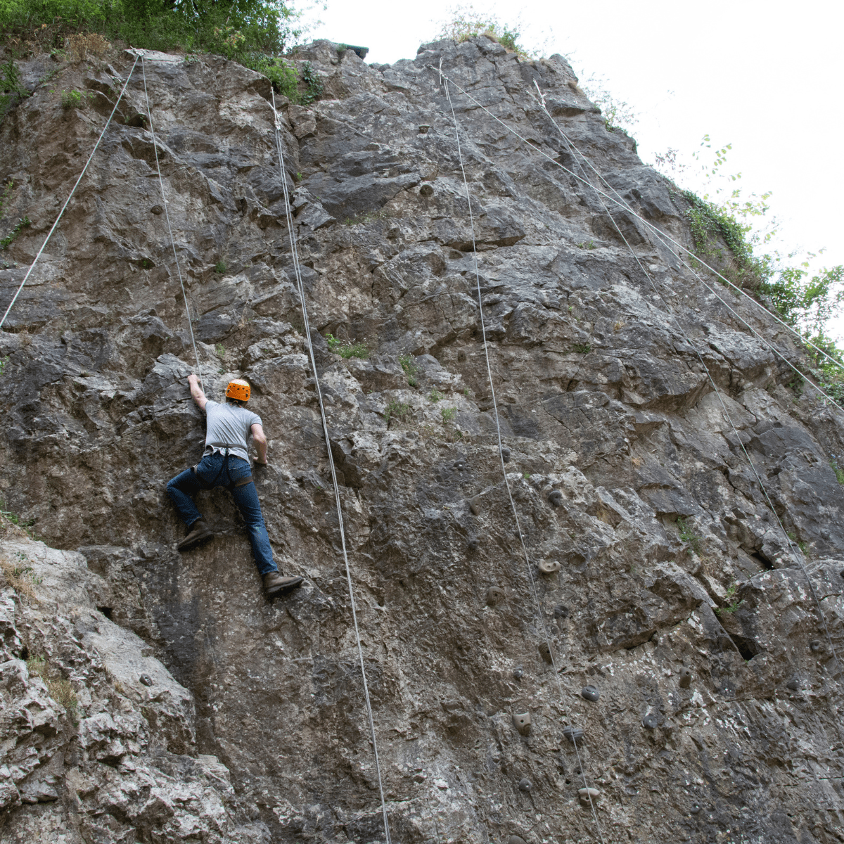 A person impressively climbs up one of the rock formations at Cheddar, nearing the top