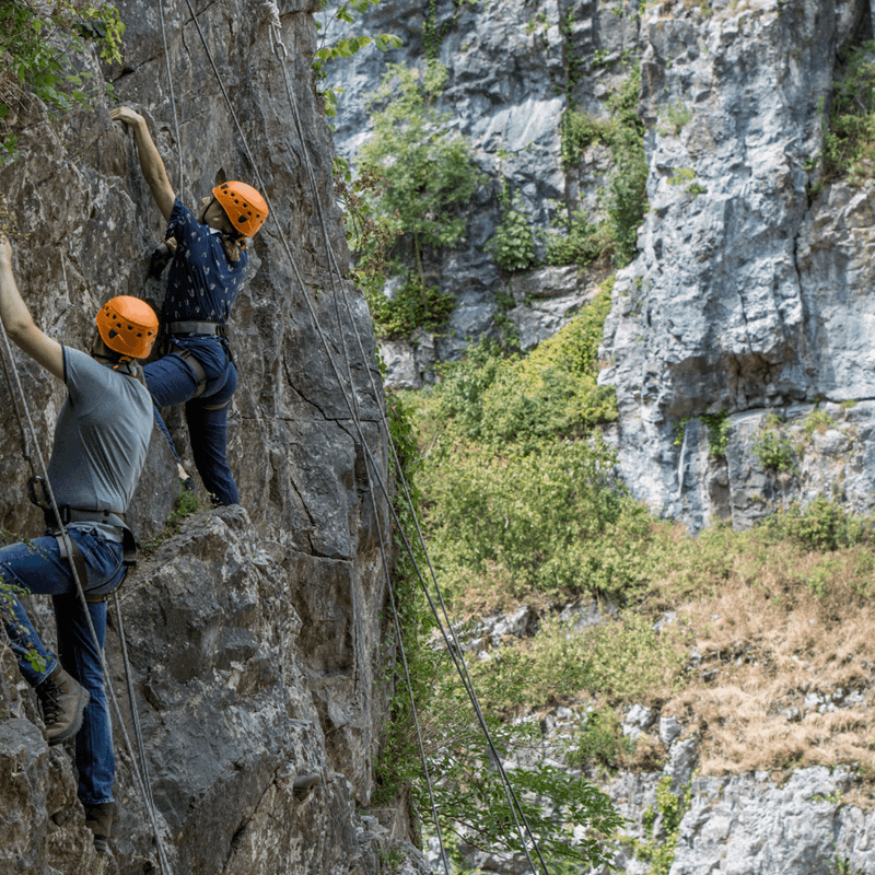 Two people climb the rock at Cheddar with its impressive formations and scale