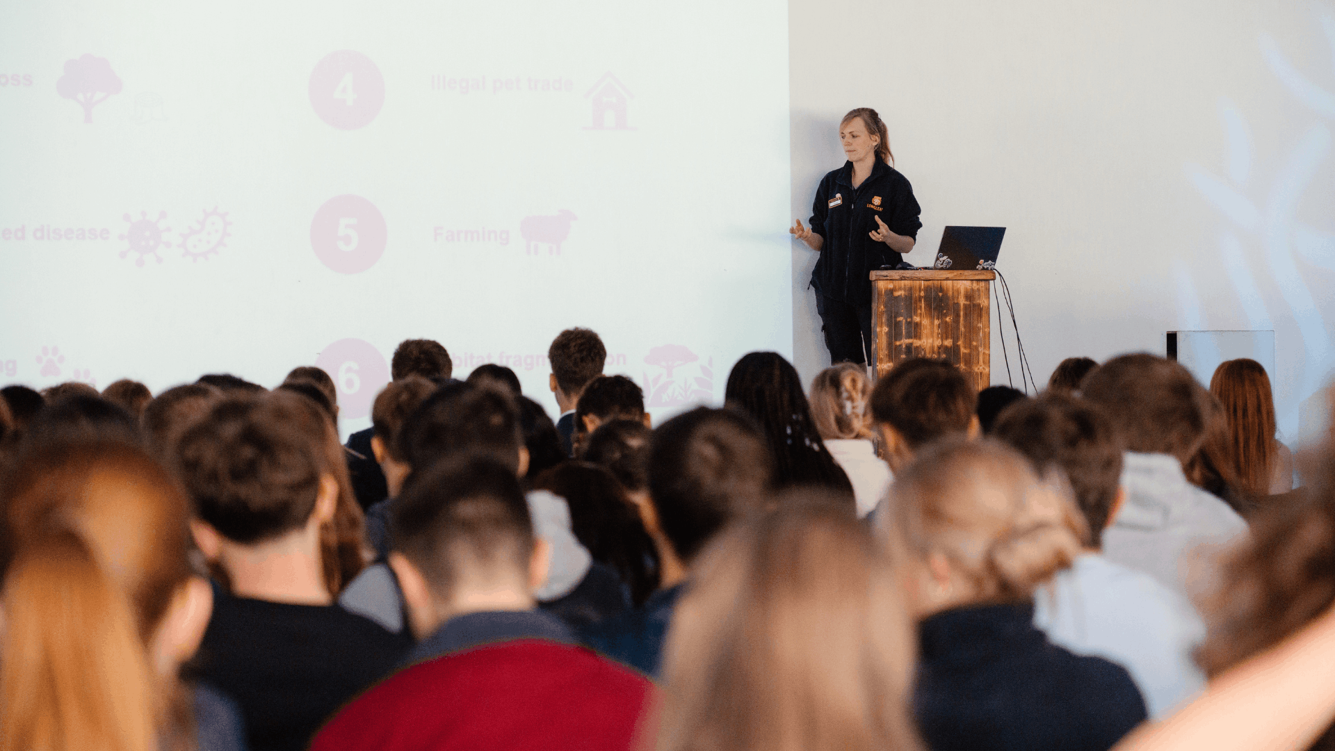 A Longleat staff member standing at a lectern presenting to a large group of students