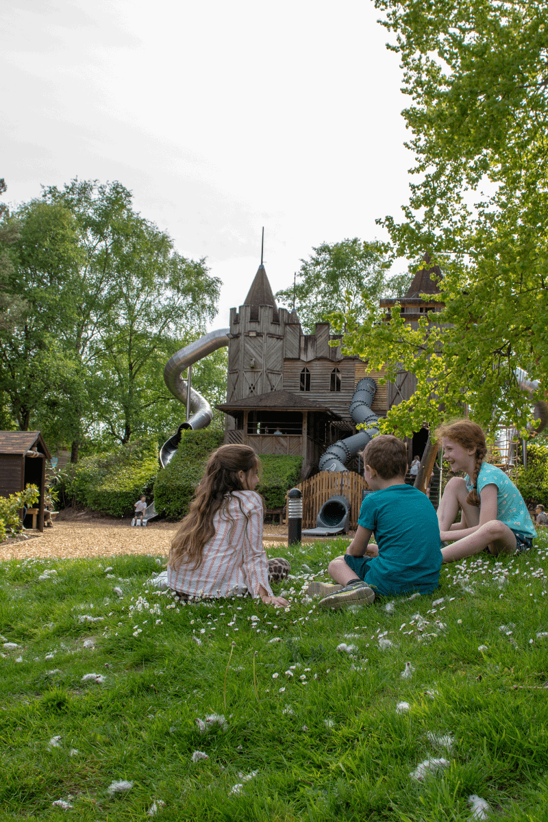 Three children sitting on the grass in the Adventure Caste with the Medieval Keep in the background