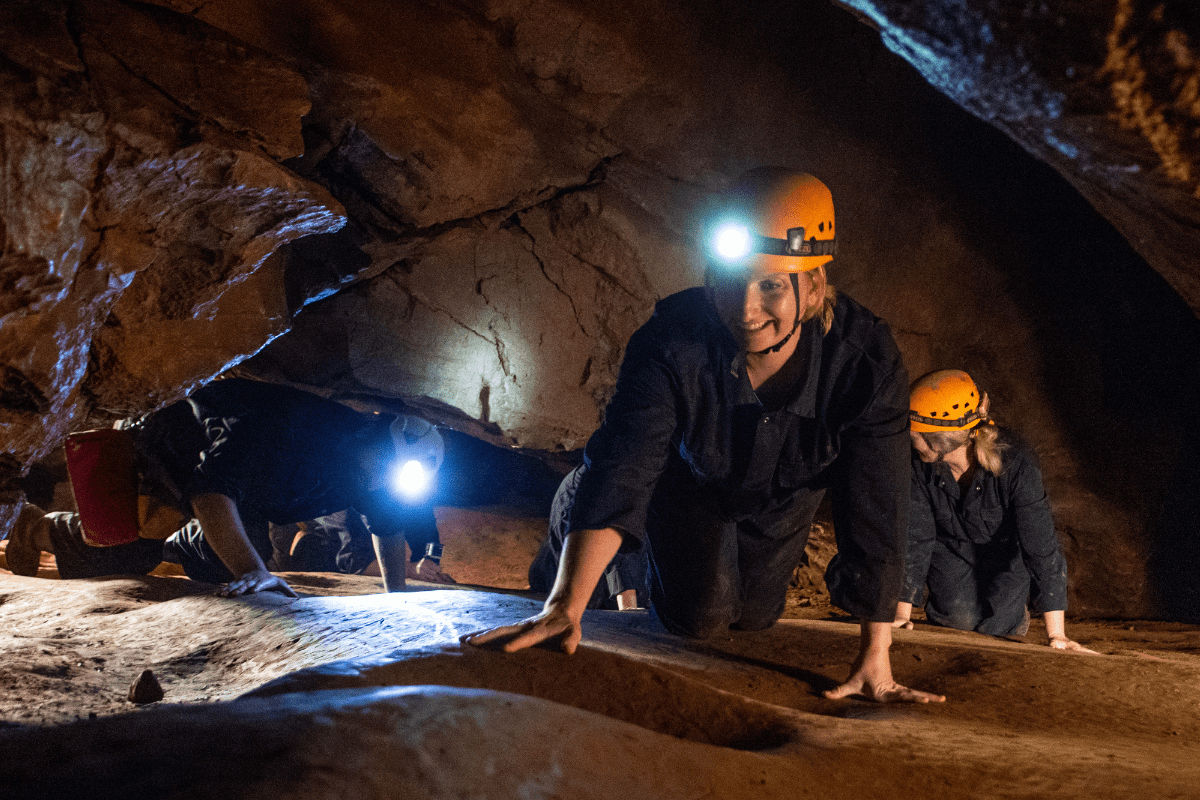 A group of Adventure Cavers enjoy navigating the cave with their head torches leading the way