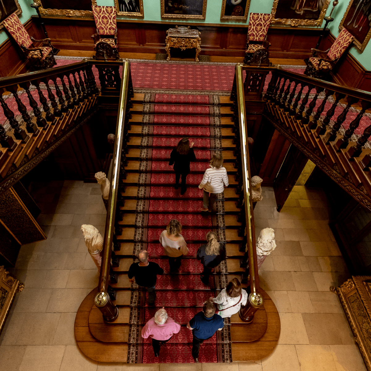 A group of visitors ascend the stairs of Longleat House whilst on a guided tour
