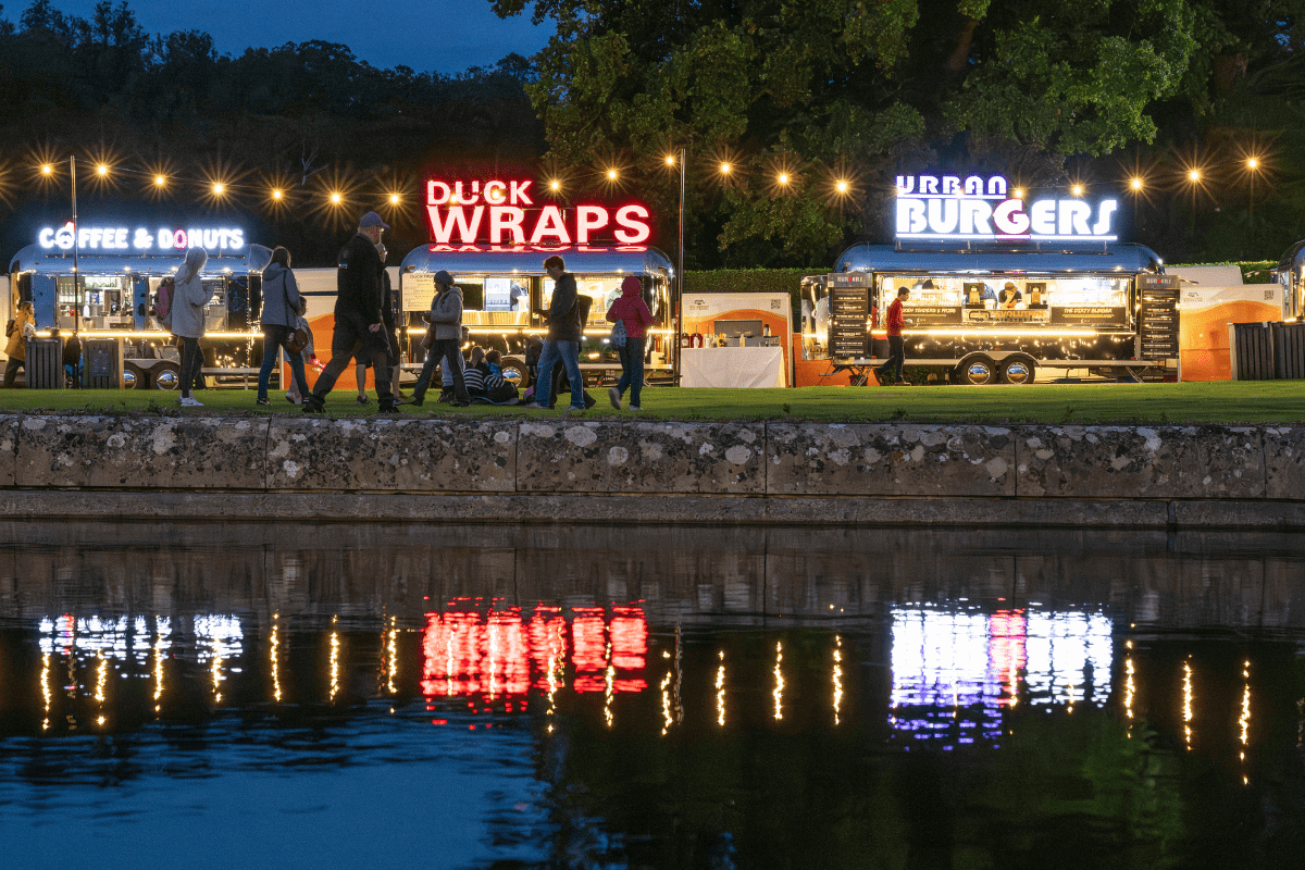 three food stalls at night time, reflected in the fountain water