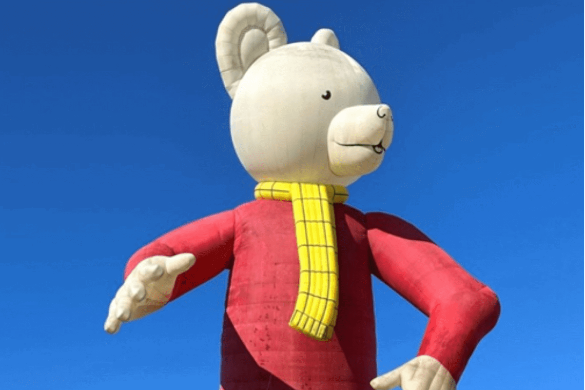 A balloon shaped as Ruper the bear, a white bear with a red top and yellow tartan trousers