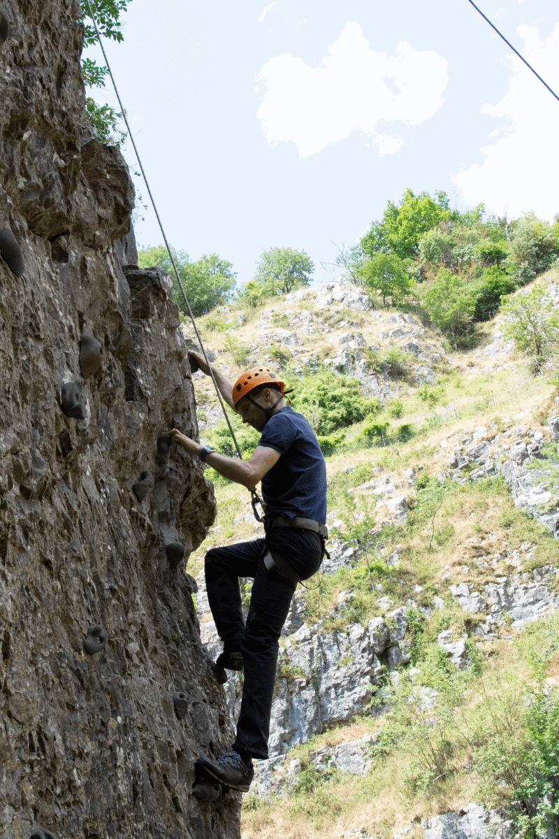 A visitor enjoys a climb on one of the Cheddar Rock formations