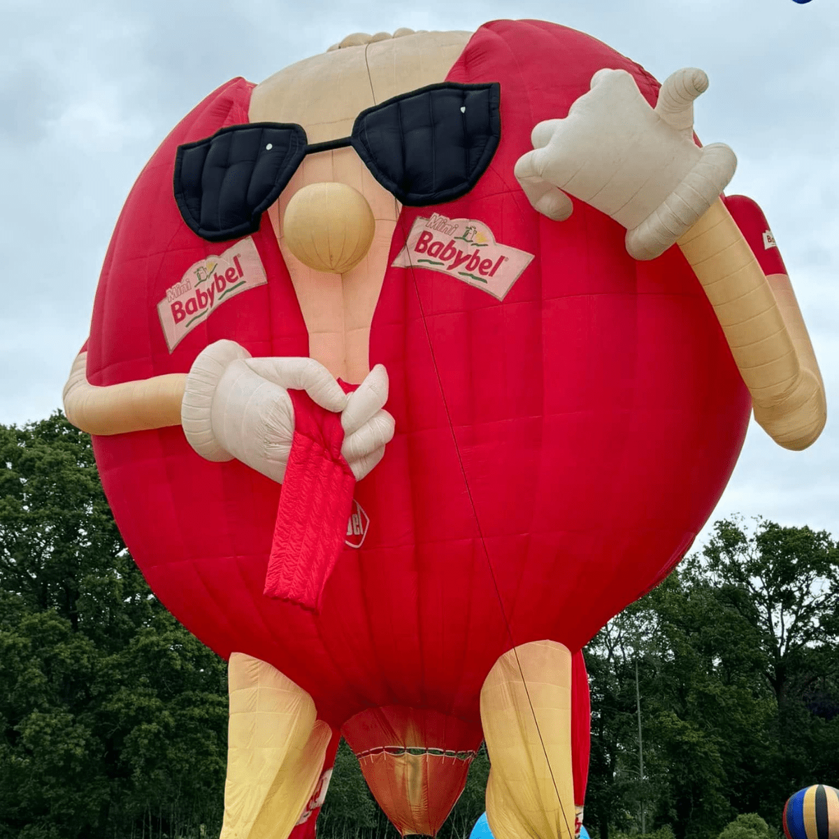A balloon shaped as a babybel with sunglasses on