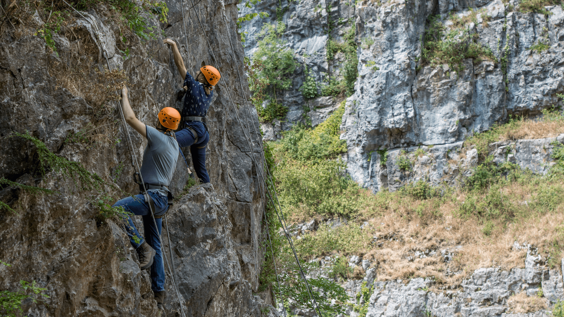 Two visitors climb one of the rock formations at Cheddar