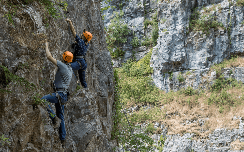 Two visitors climb one of the rock formations at Cheddar