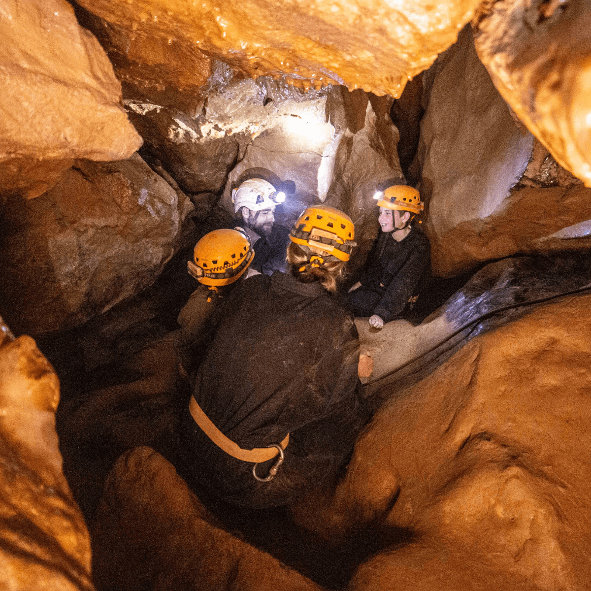 A group enjoy Adventure Caving, with their head torches lighting up the unique cave formations