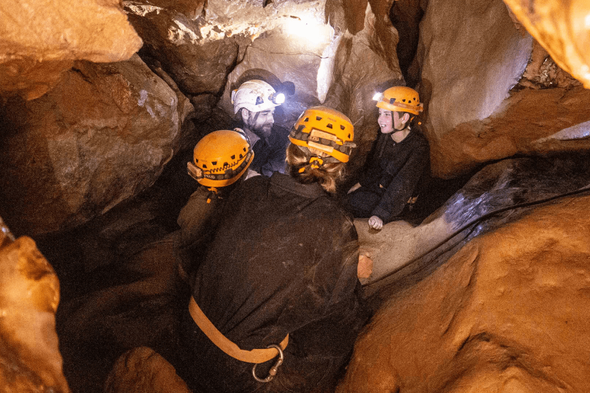 A group enjoy Adventure Caving, with their head torches lighting up the unique cave formations