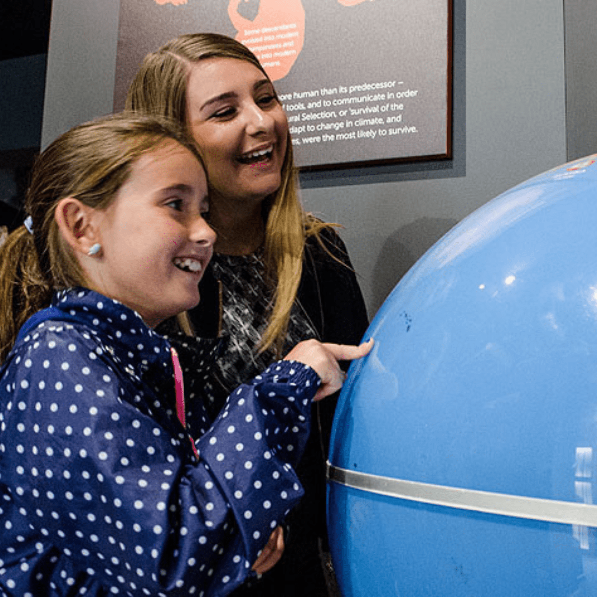 An adult and child look at a globe at the museum of prehistory