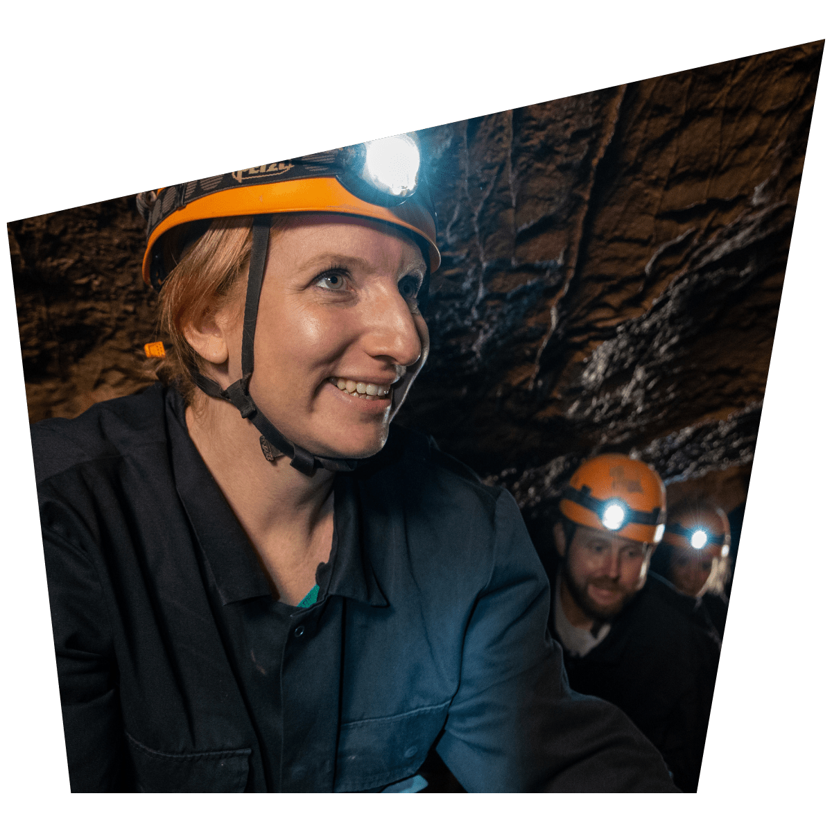 A group enjoy Adventure Caving, with their head torches lighting up the unique cave formations