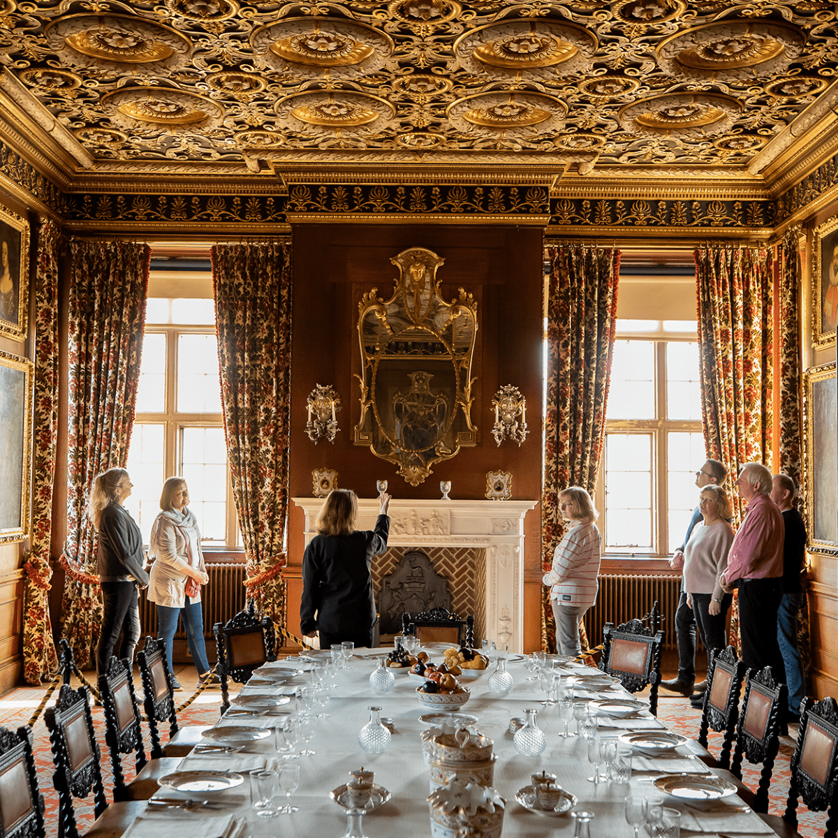 A group of visitors admire the grand ceiling in one of the dining rooms whilst on a guided tour of Longleat House