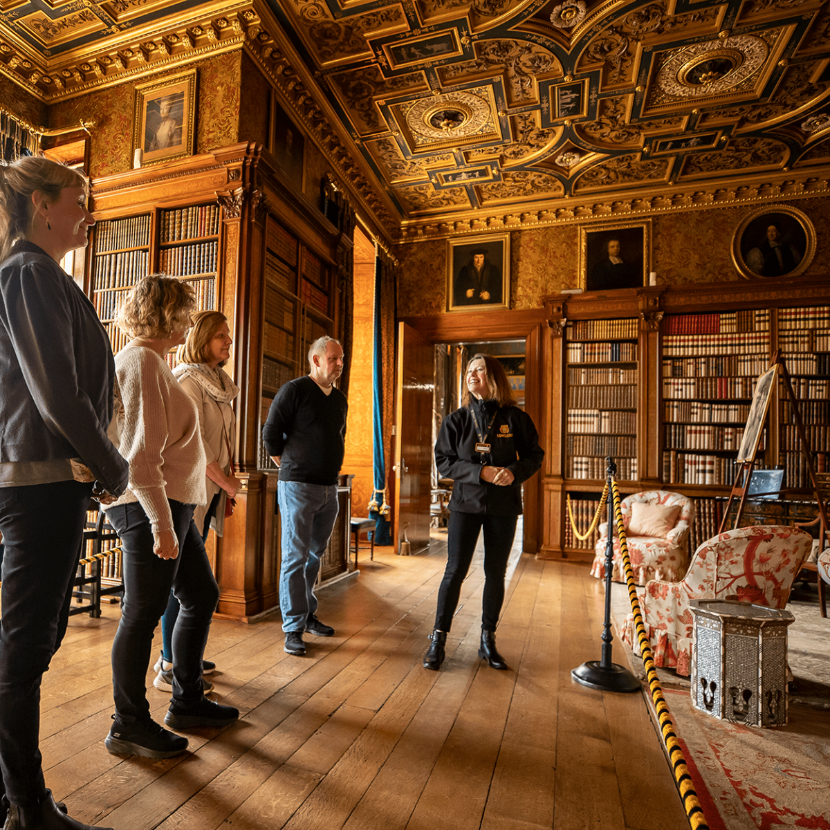 A Longleat House Guide delivers a tour to a group of people within one of the grand libraries
