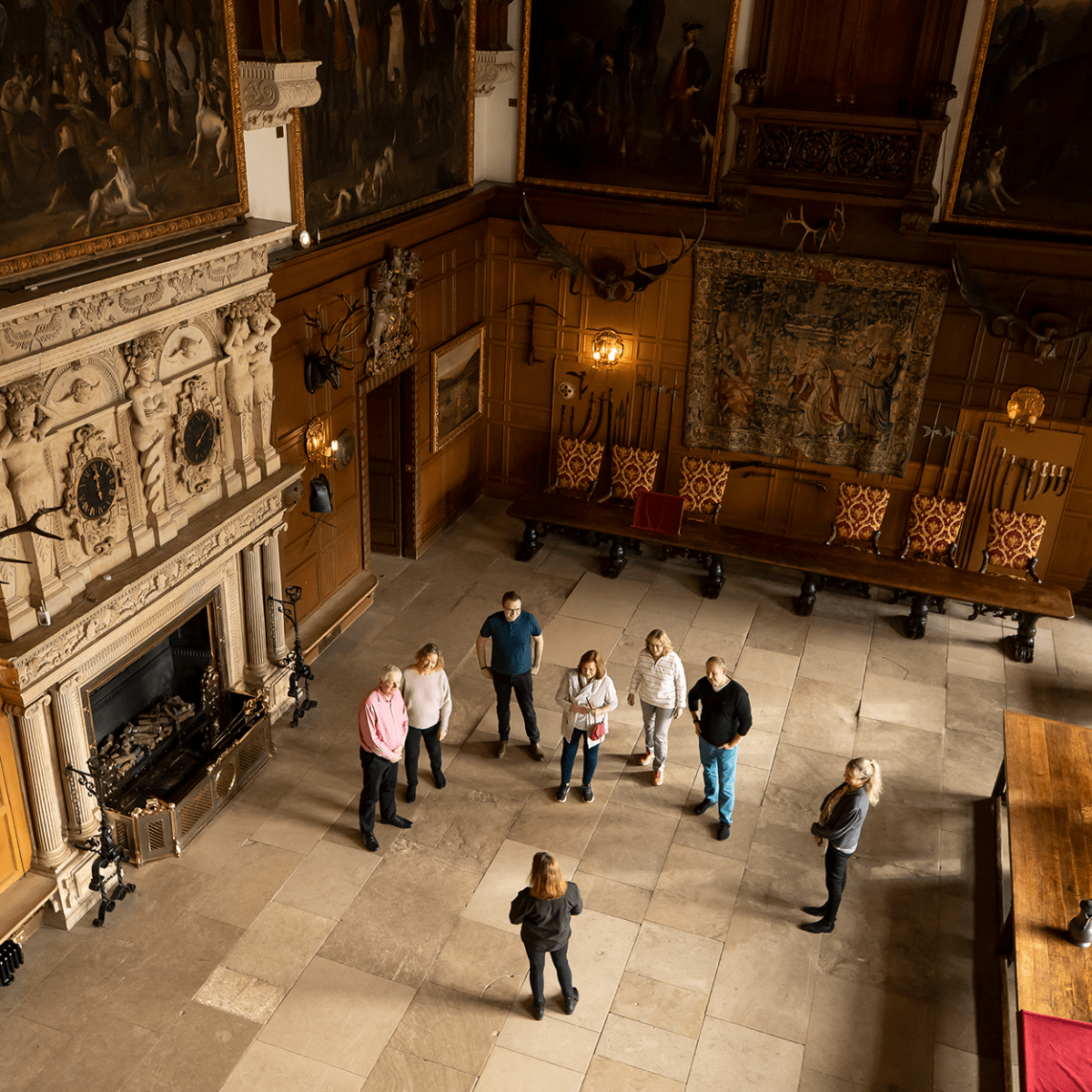 A group of visitors admire the great hall whilst listening intently to the house guide