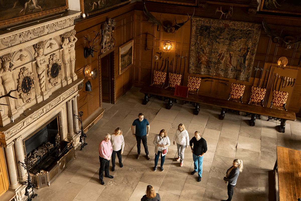 A group of visitors admire the great hall whilst listening intently to the house guide