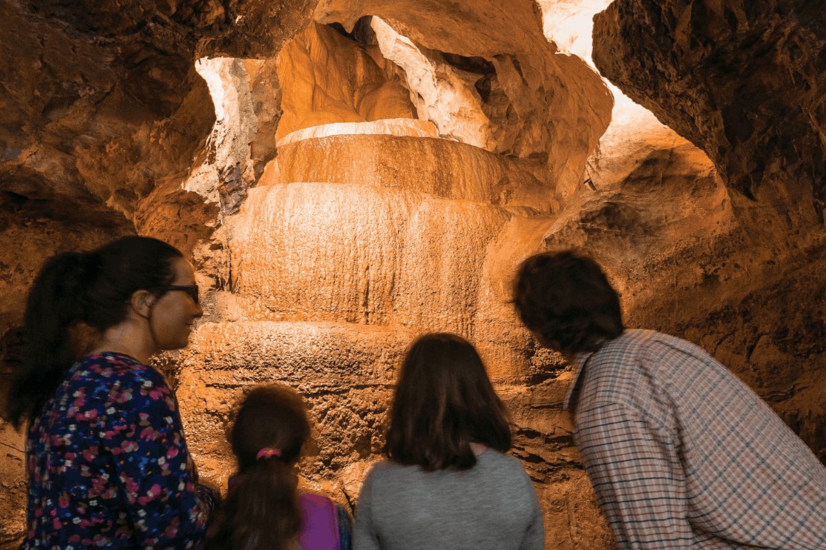 A family (from behind) looking at a rock formation within a cave