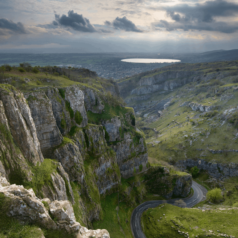 A panoramic shot of Cheddar gorge with its sweeping natural landscape and stormy sky in the distance