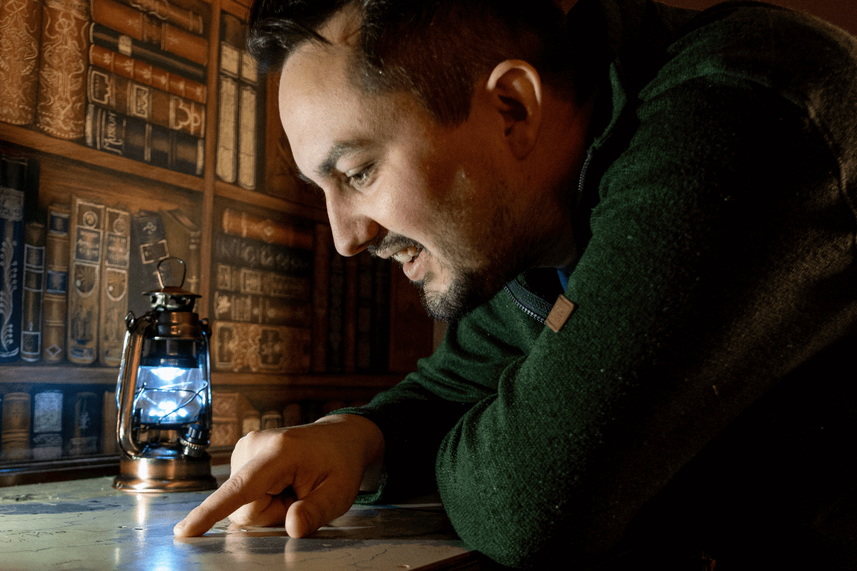 A man looks at a potential clue in the escape rooms at Cheddar. He peers at a map looking for answers