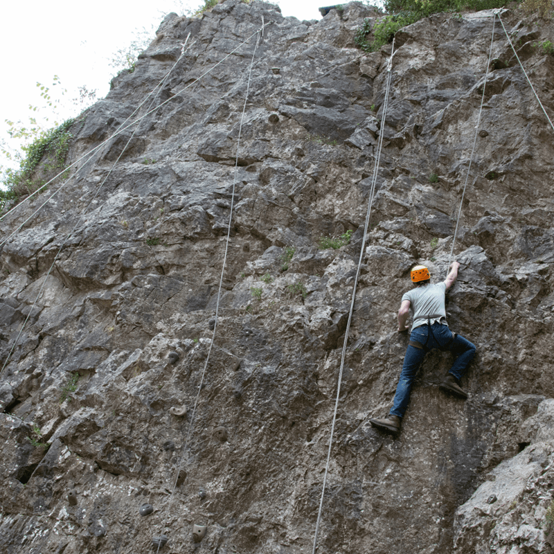 A visitor scales one of the rock formations at Cheddar Gorge & Caves