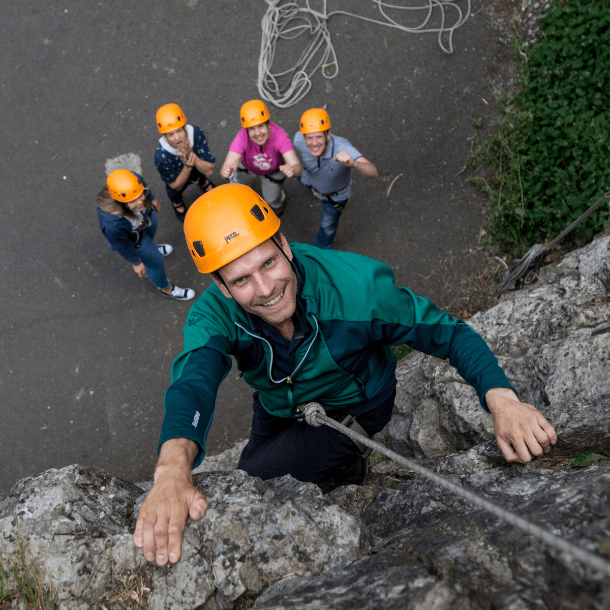 A visitor to Cheddar Gorge & Caves climbs one of the rock formations, with their team looking on in support and cheering