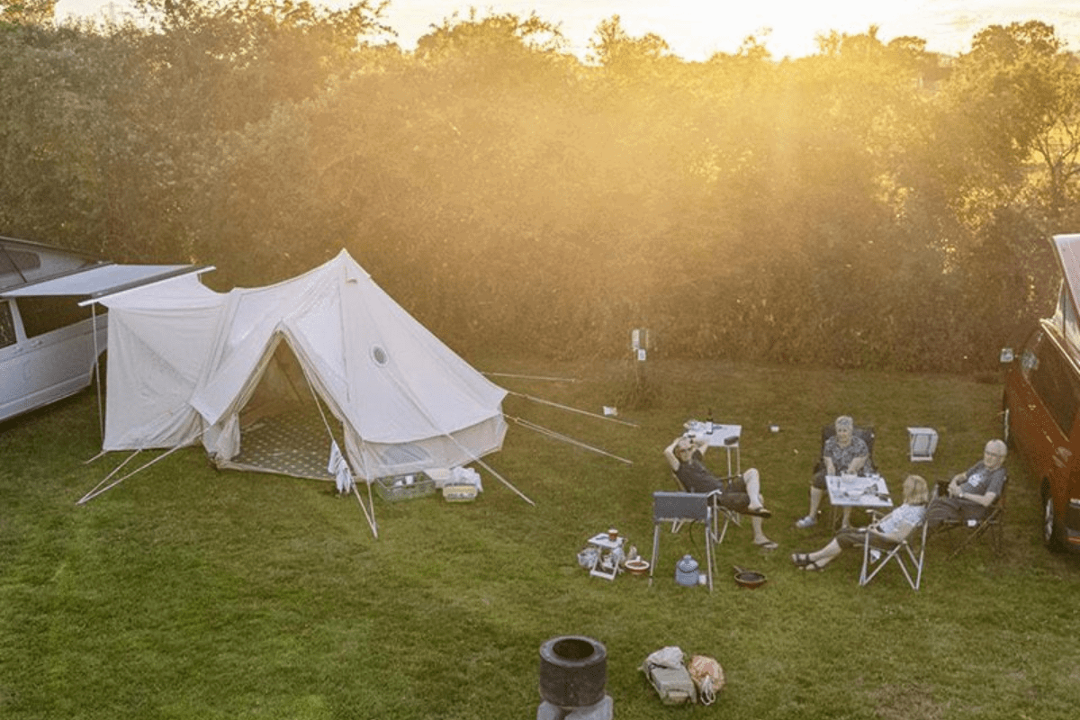 A group enjoy the outdoors as they sit next to their tent set up at Greenacres camping